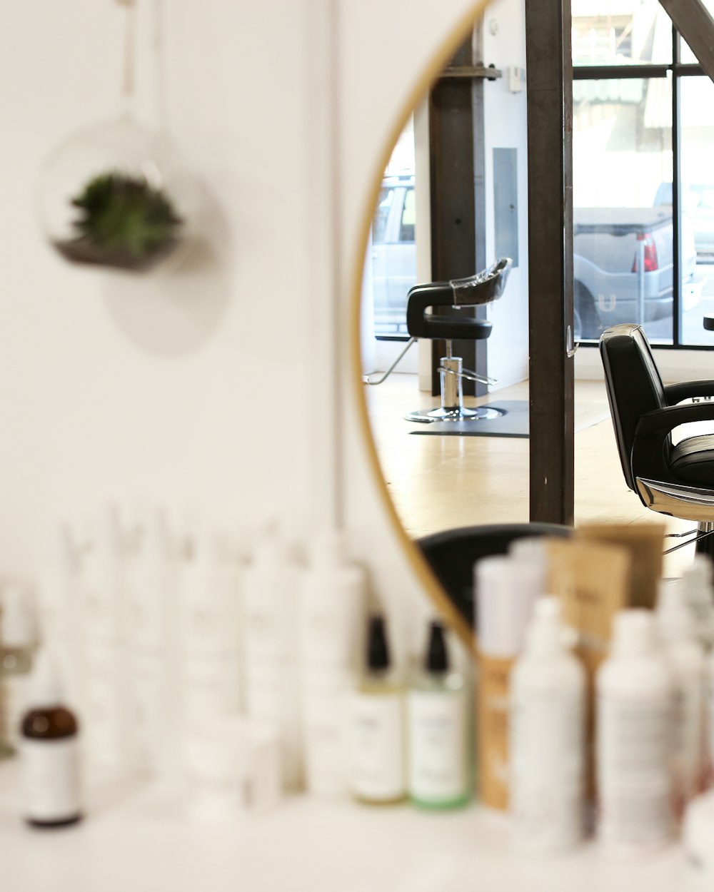 丸い鏡とヘアケア用品が並ぶ、白を基調としたセット面